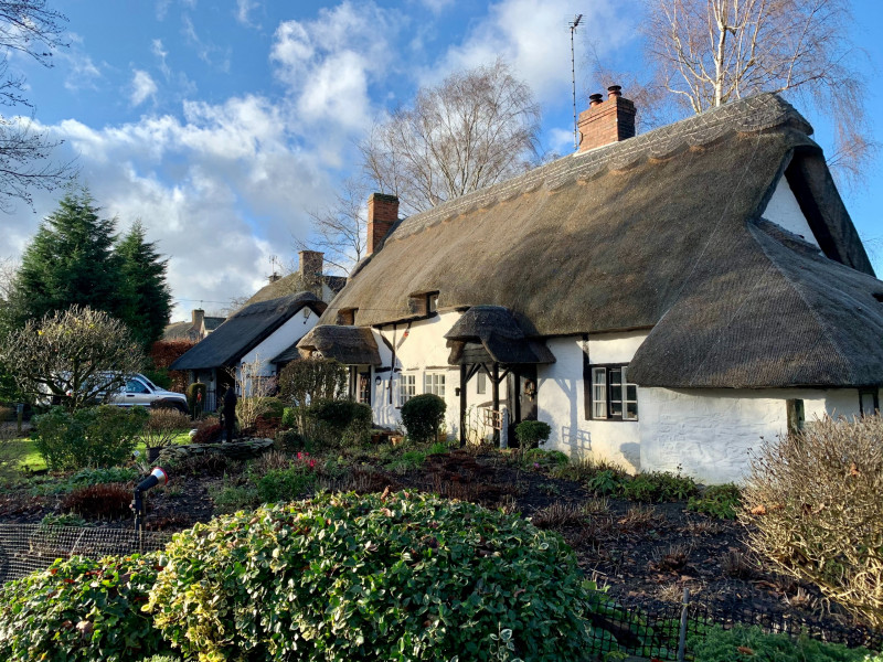 Exterior cottage with a thatched roof, windows and walls painted